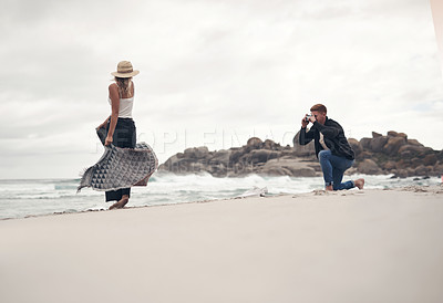Buy stock photo Shot of a man taking pictures of his girlfriend while spending time at the beach