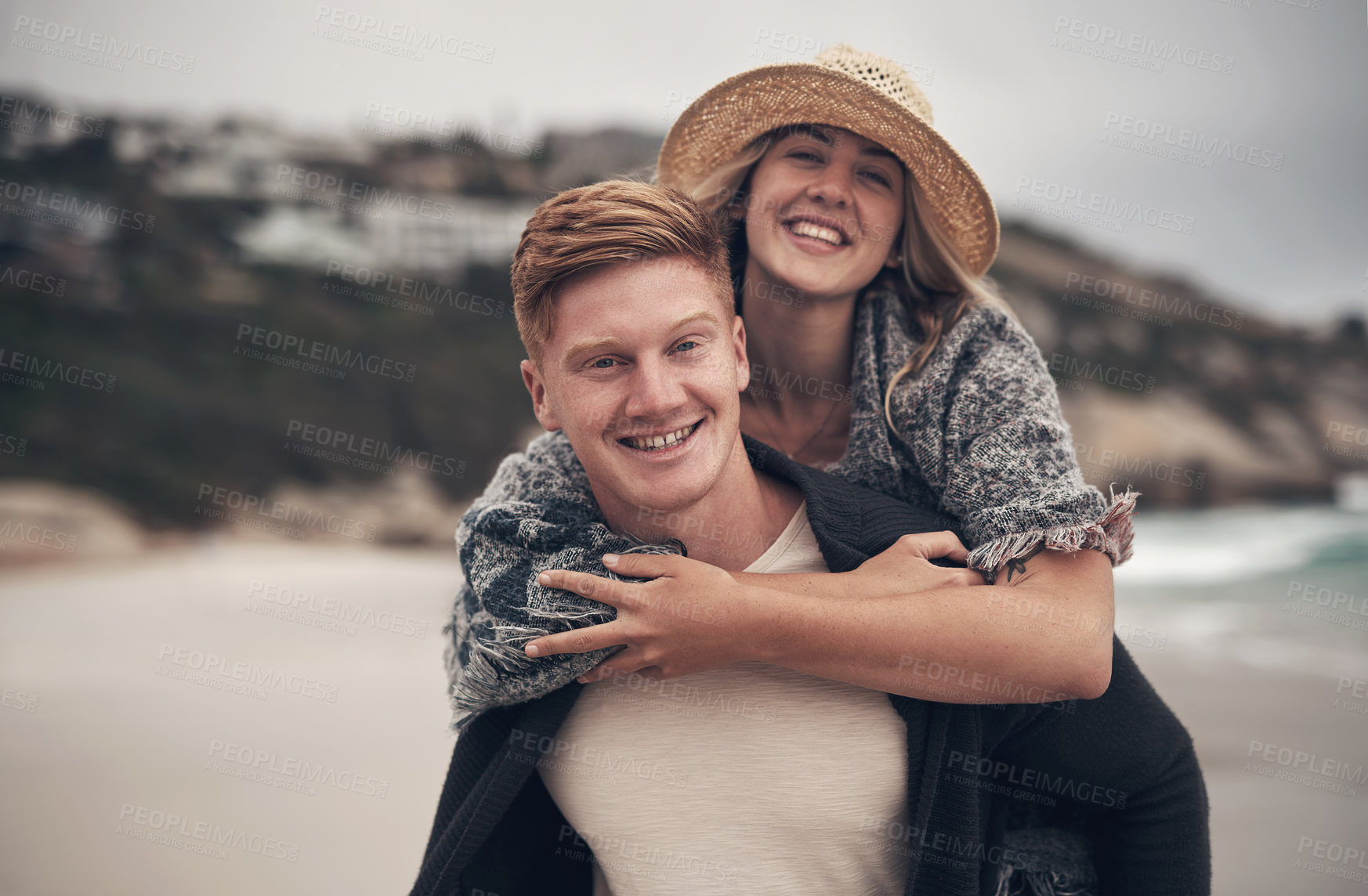 Buy stock photo Shot of a man piggybacking his girlfriend while walking on the beach