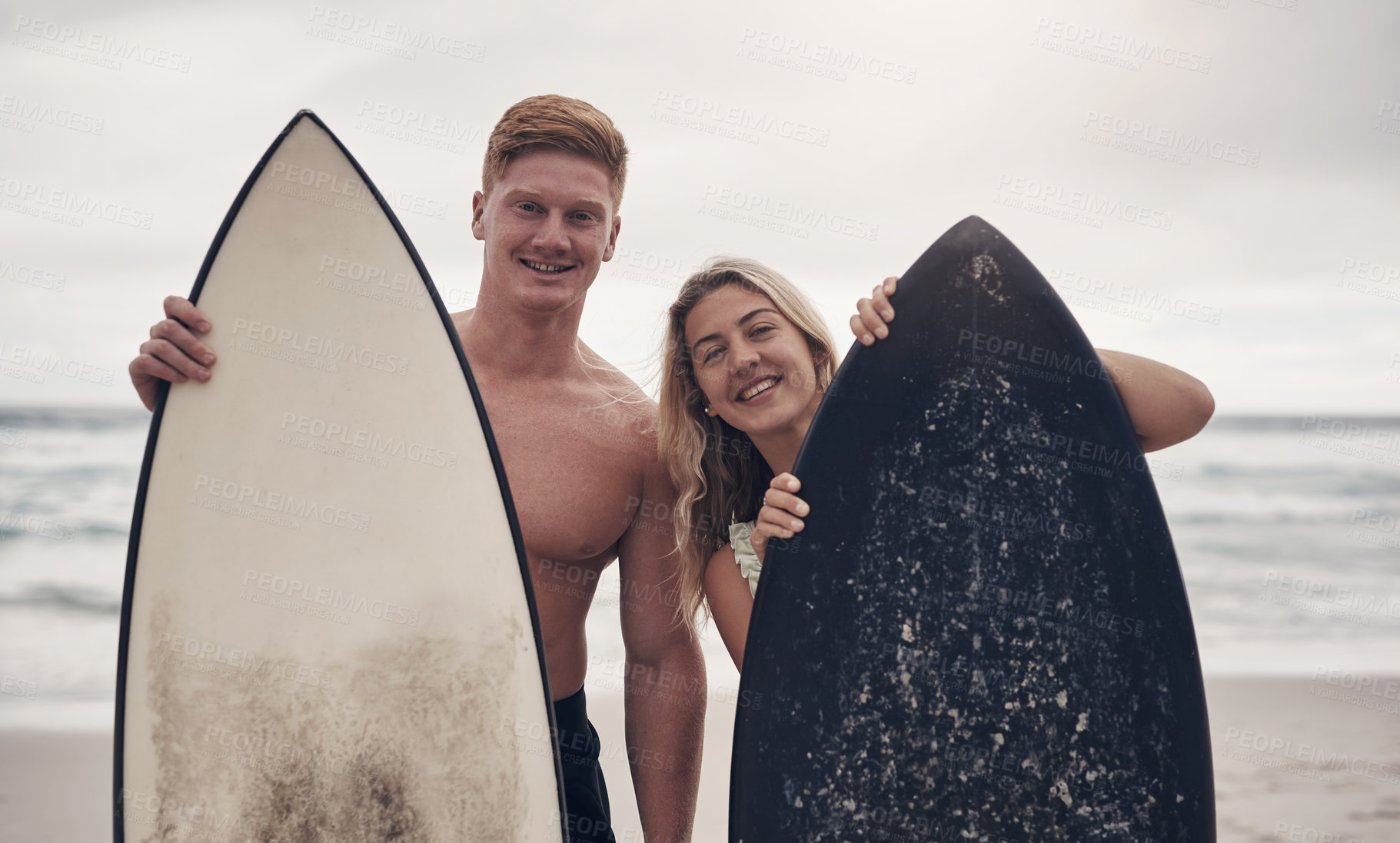 Buy stock photo Shot of a couple out at the beach with their surfboards