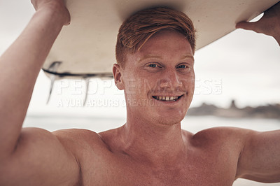 Buy stock photo Shot of a young man carrying his surfboard on his head while at the beach