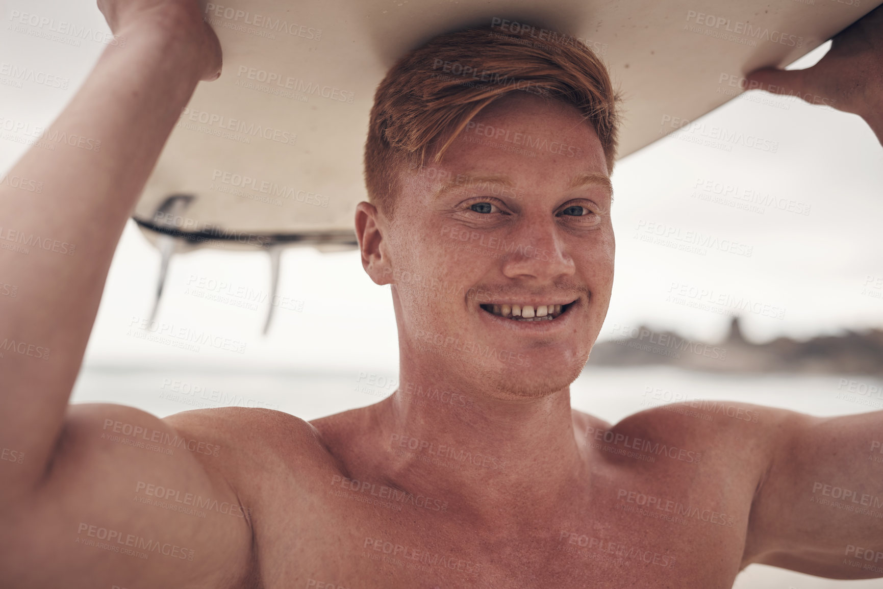 Buy stock photo Shot of a young man carrying his surfboard on his head while at the beach