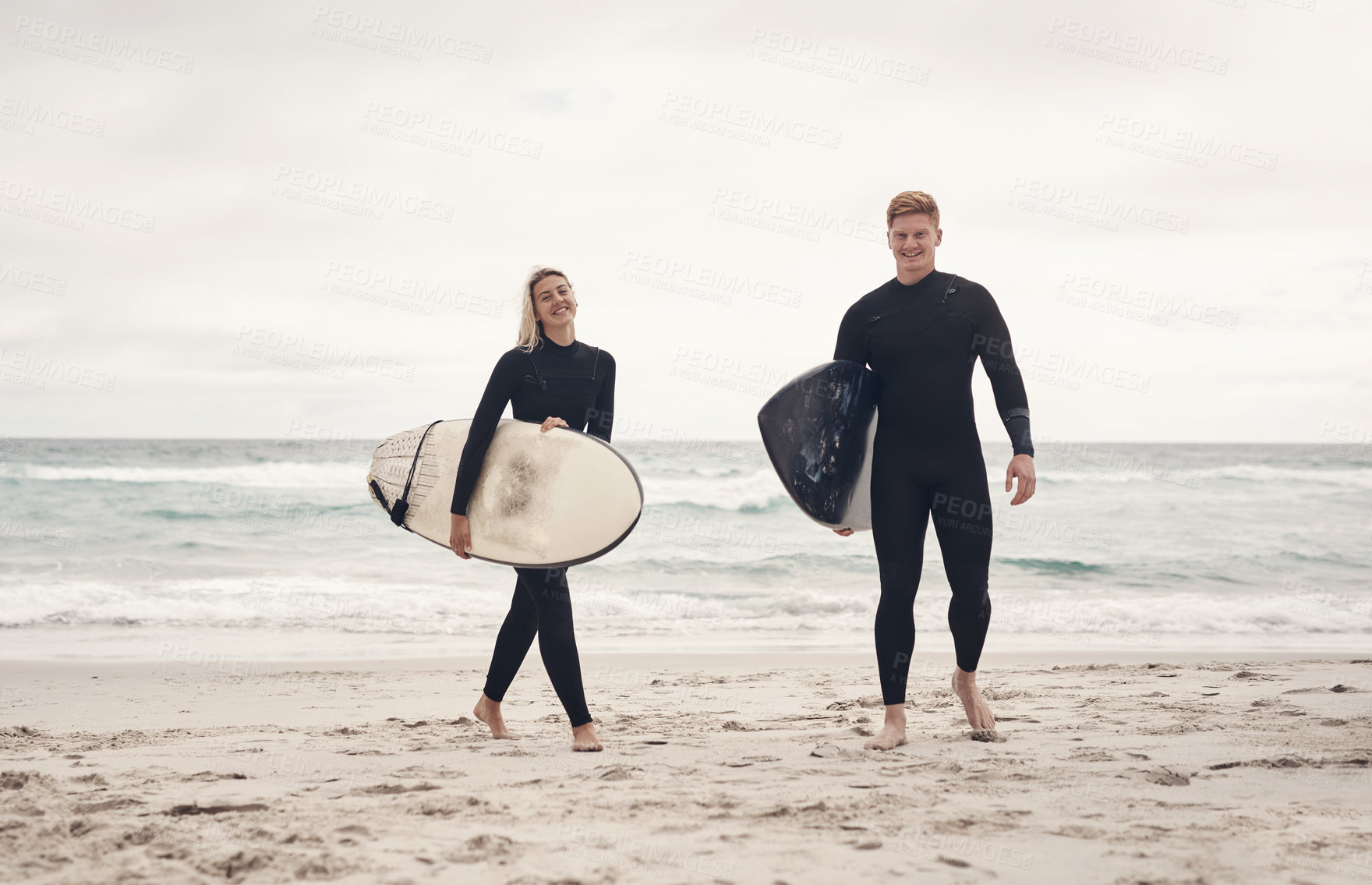 Buy stock photo Shot of a young couple out at the beach with their surfboards