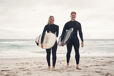 Buy stock photo Shot of a young couple out at the beach with their surfboards