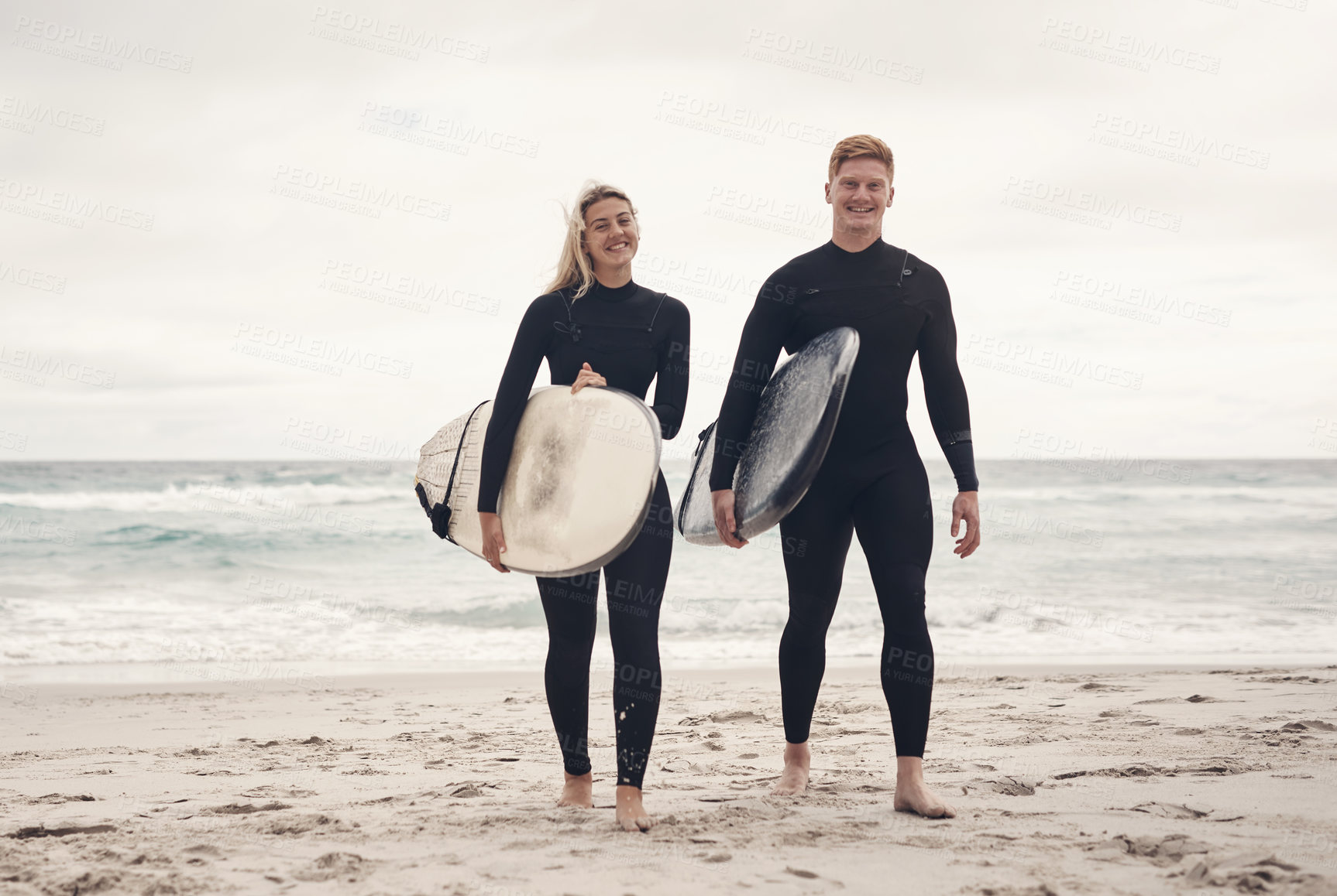 Buy stock photo Shot of a young couple out at the beach with their surfboards