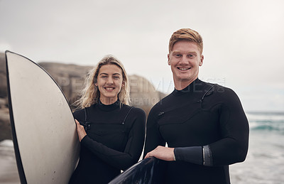 Buy stock photo Shot of a young couple out at the beach with their surfboards