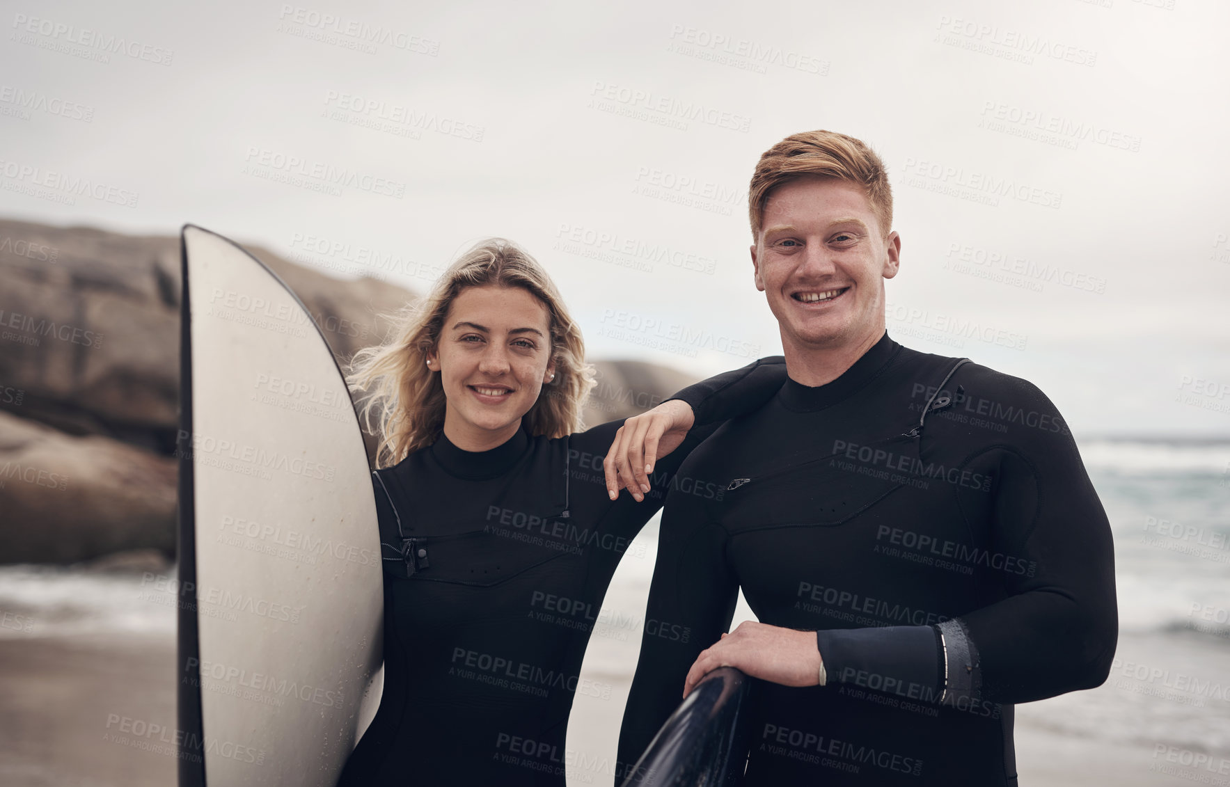 Buy stock photo Shot of a young couple out at the beach with their surfboards