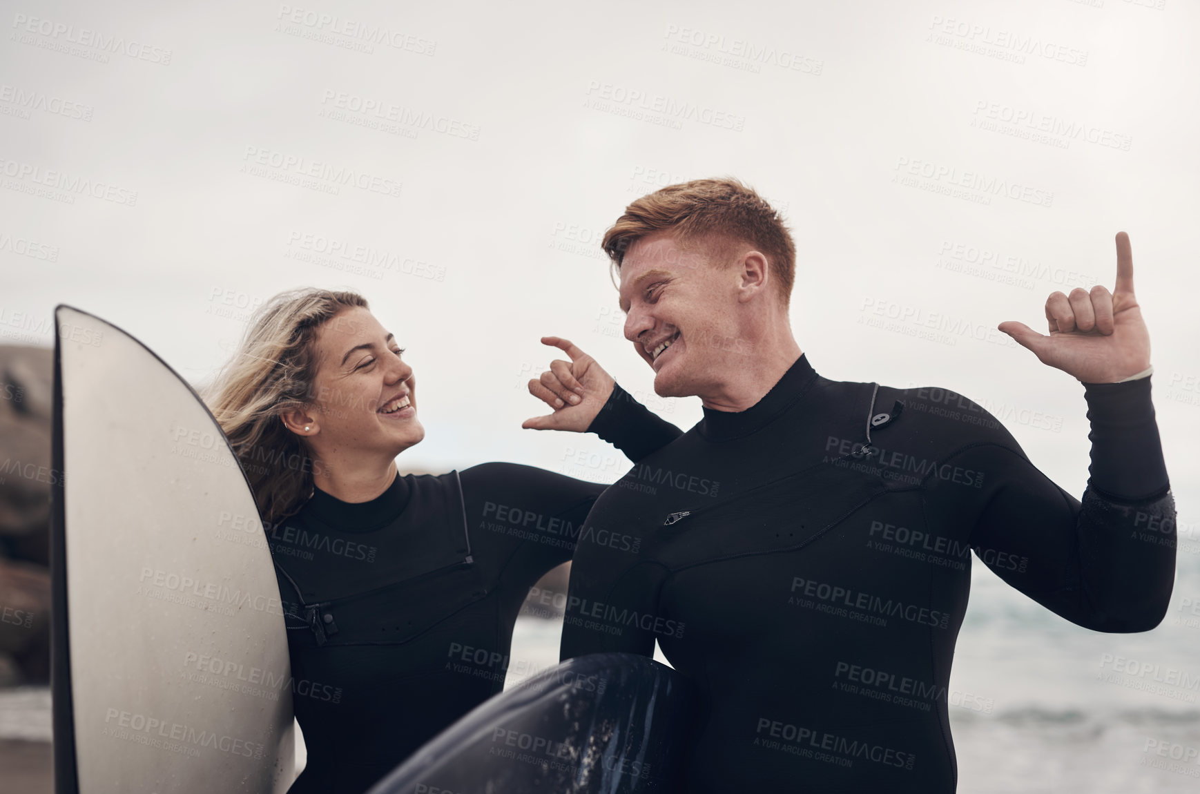 Buy stock photo Shot of a young couple out at the beach with their surfboards