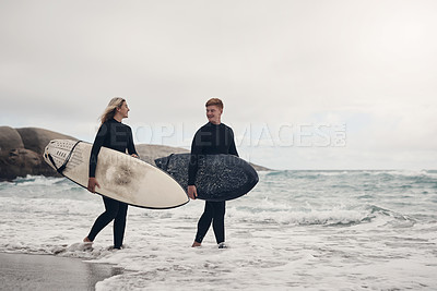 Buy stock photo Shot of a young couple out at the beach with their surfboards