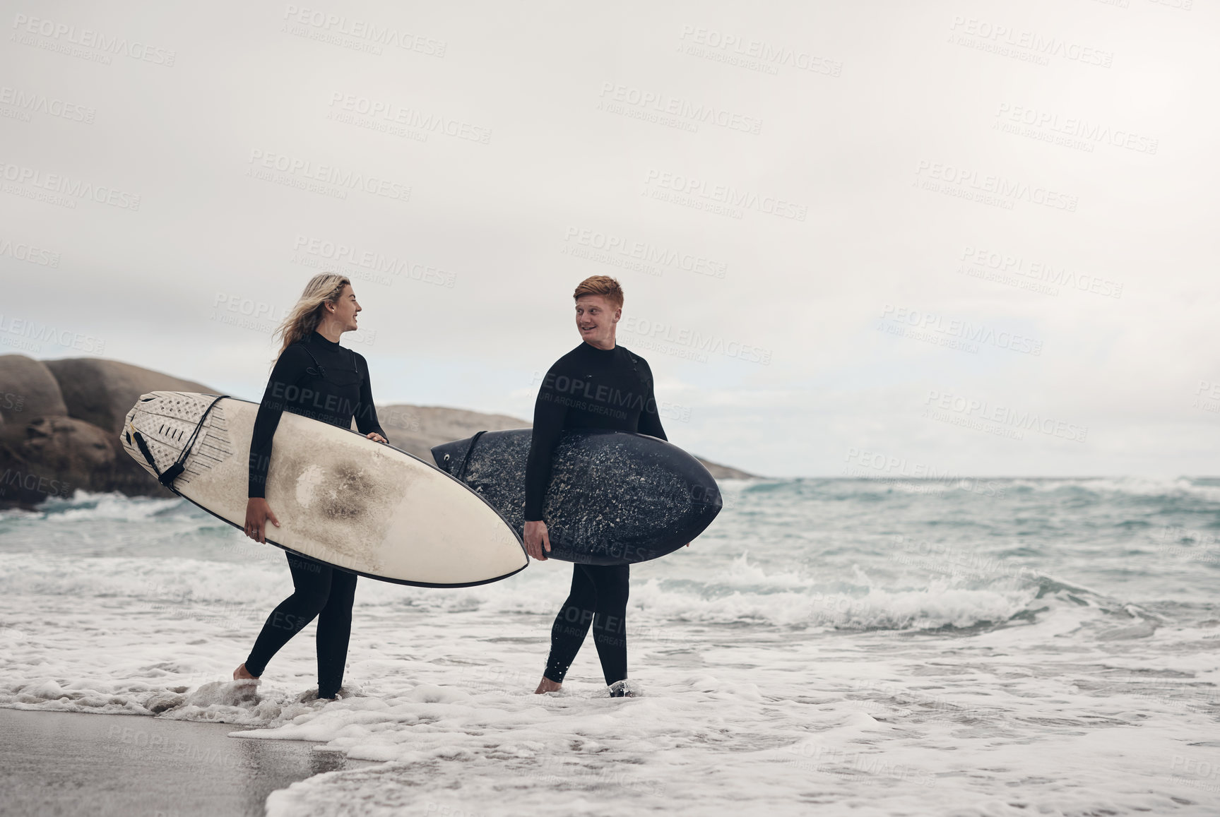 Buy stock photo Shot of a young couple out at the beach with their surfboards