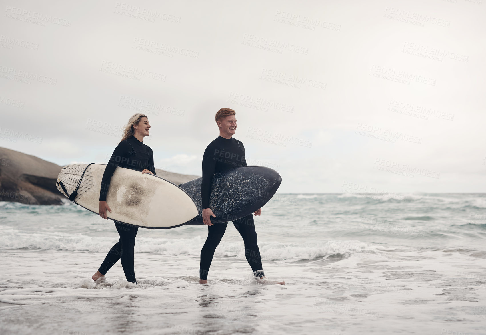 Buy stock photo Shot of a young couple out at the beach with their surfboards