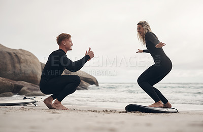 Buy stock photo Shot of a man giving a woman surfing lessons on the beach