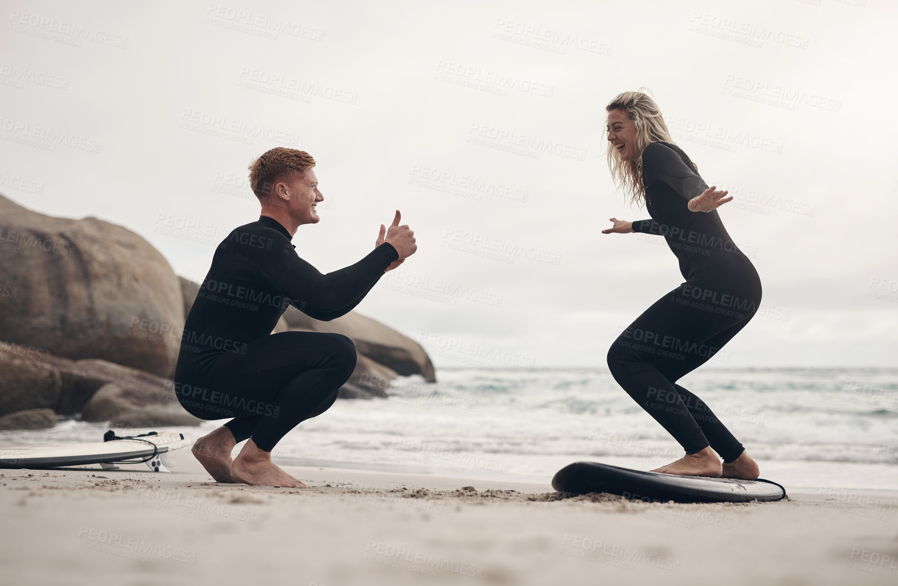 Buy stock photo Shot of a man giving a woman surfing lessons on the beach