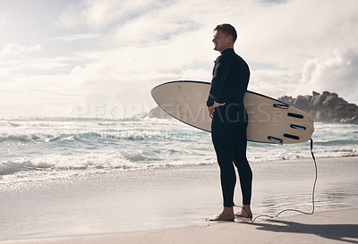 Buy stock photo Shot of a young man holding his surfboard while at the beach