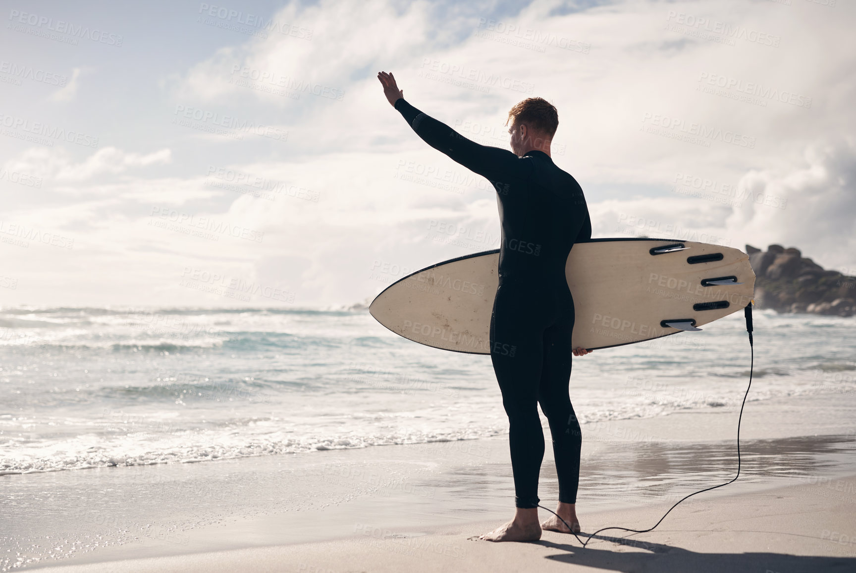 Buy stock photo Shot of a young man holding his surfboard while at the beach