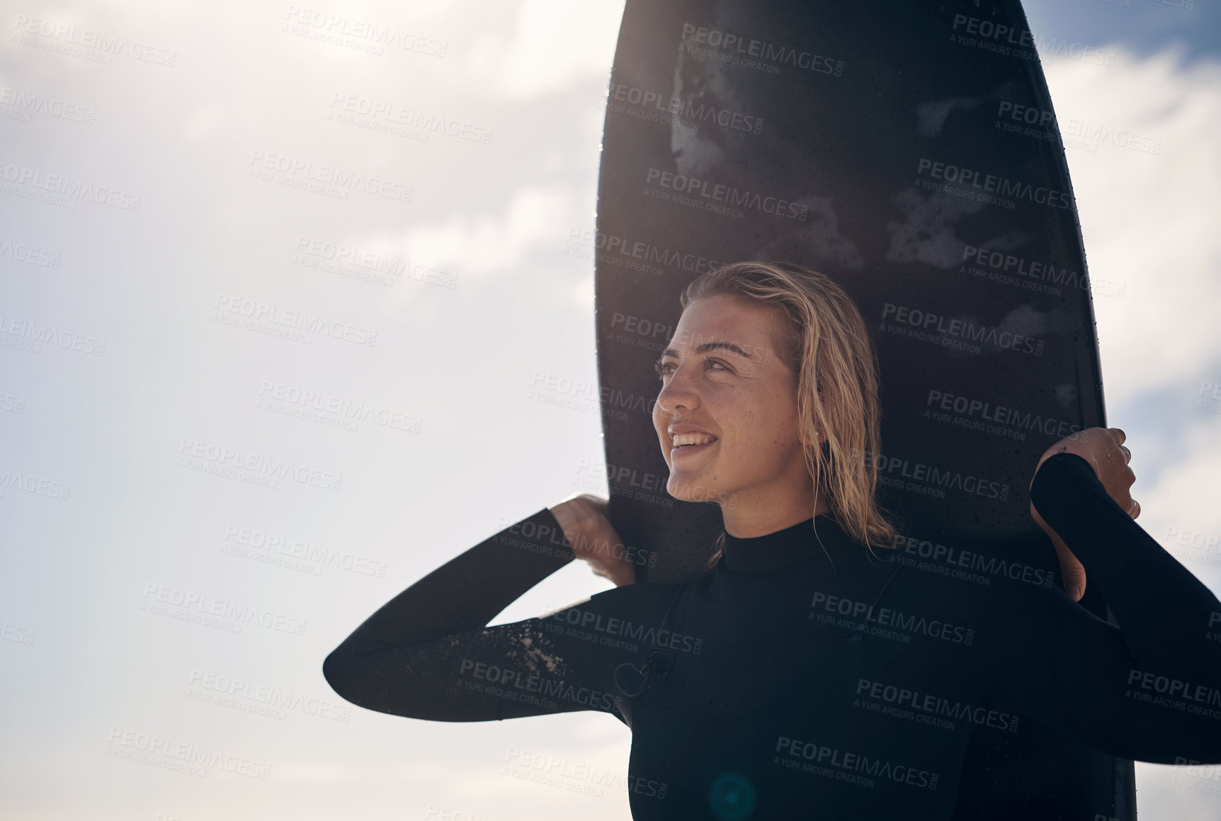 Buy stock photo Cropped shot of a young woman standing on the beach with her surfboard