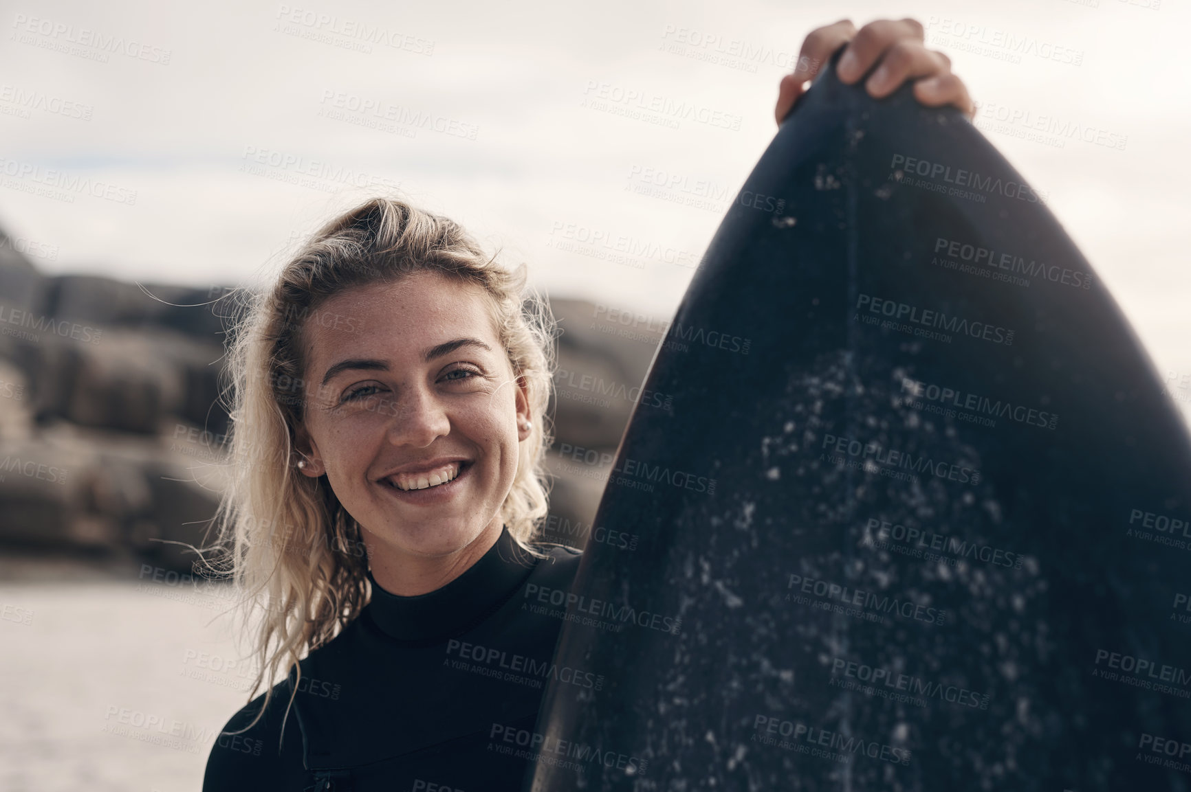 Buy stock photo Cropped shot of a young woman standing on the beach with her surfboard