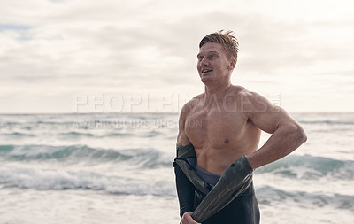 Buy stock photo Cropped shot of a young man taking off his wetsuit