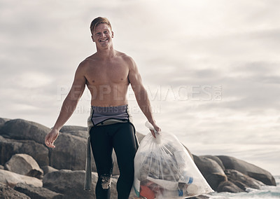 Buy stock photo Shot of a man carrying a bag of trash after cleaning up the beach