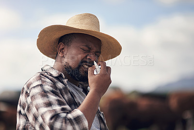 Buy stock photo Shot of a mature man using nasal spray while working on a farm