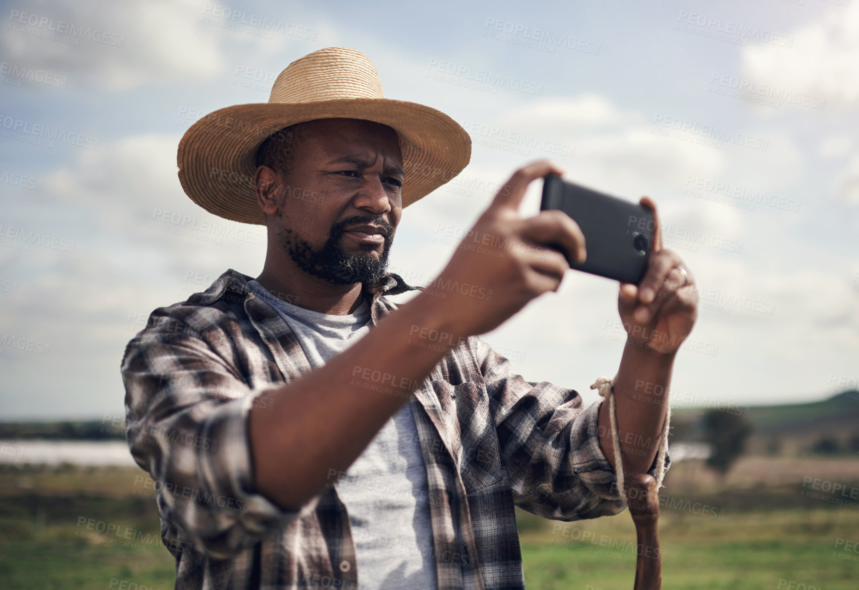 Buy stock photo Shot of a mature man using a smartphone to take pictures of a farm