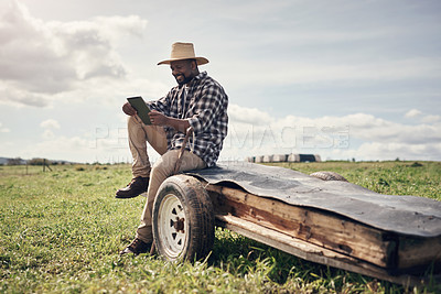 Buy stock photo Shot of a mature man using a digital tablet while working on a farm