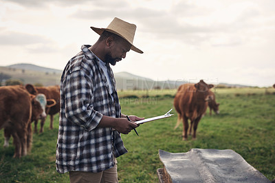 Buy stock photo Shot of a mature man writing notes while working on a cow farm