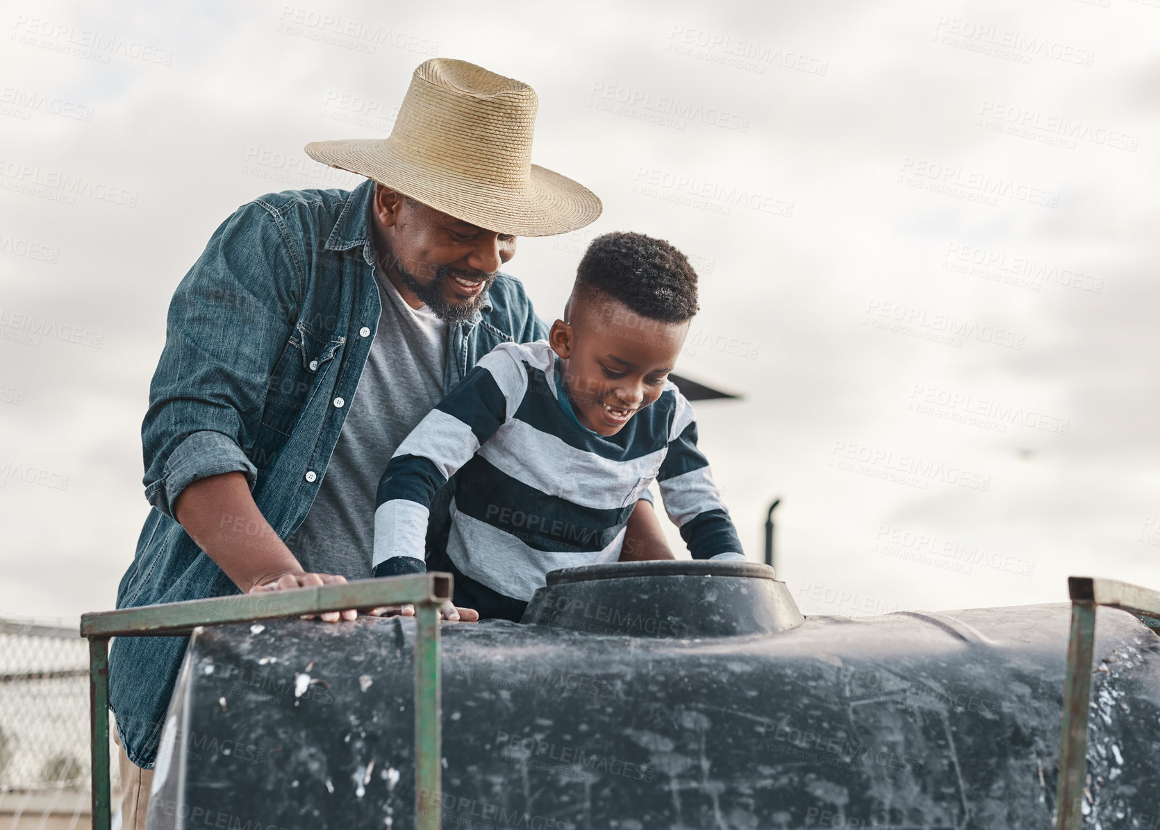 Buy stock photo Shot of a mature man helping his adorable son ride a tractor on a farm