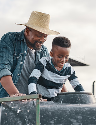 Buy stock photo Shot of a mature man helping his adorable son ride a tractor on a farm