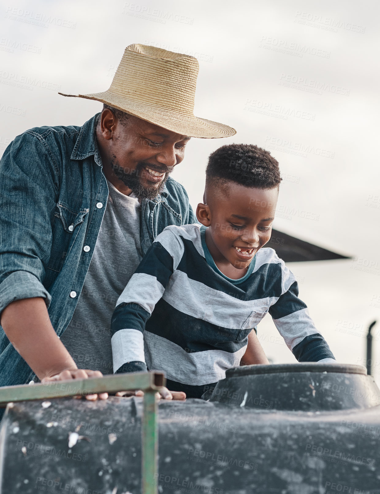 Buy stock photo Shot of a mature man helping his adorable son ride a tractor on a farm