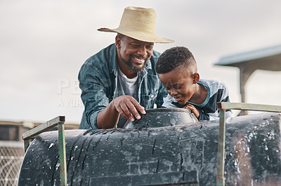 Buy stock photo Shot of a mature man helping his adorable son ride a tractor on a farm