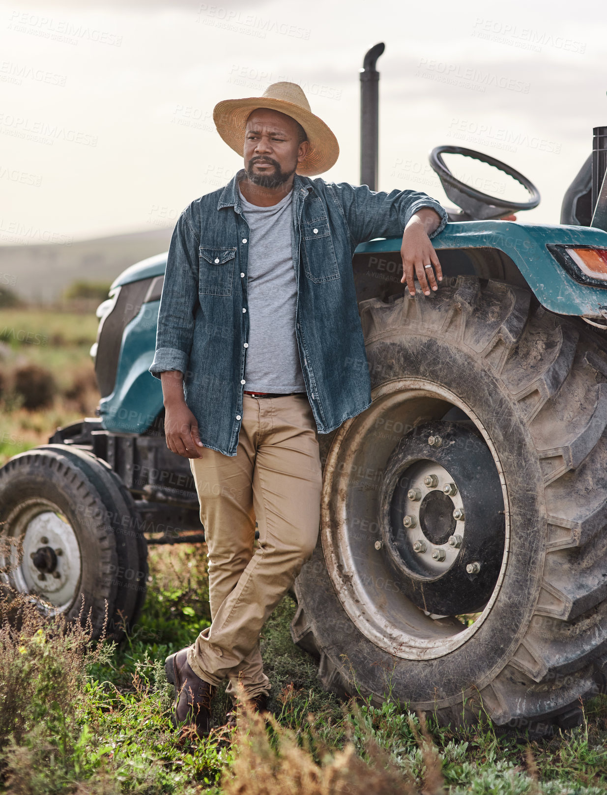 Buy stock photo Shot of a mature man standing next to his tractor on a farm