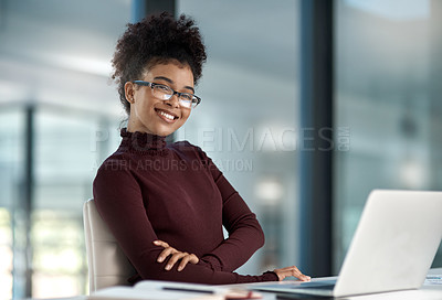 Buy stock photo Shot of a confident young businesswoman working in a modern office with her arm folded smiling