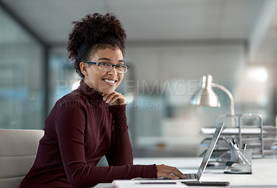 Buy stock photo Shot of a confident young businesswoman working in a modern office with her hand on her chin smiling