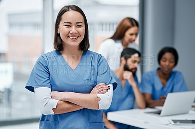 Buy stock photo Portrait of a doctor standing in a hospital with her colleagues in the background