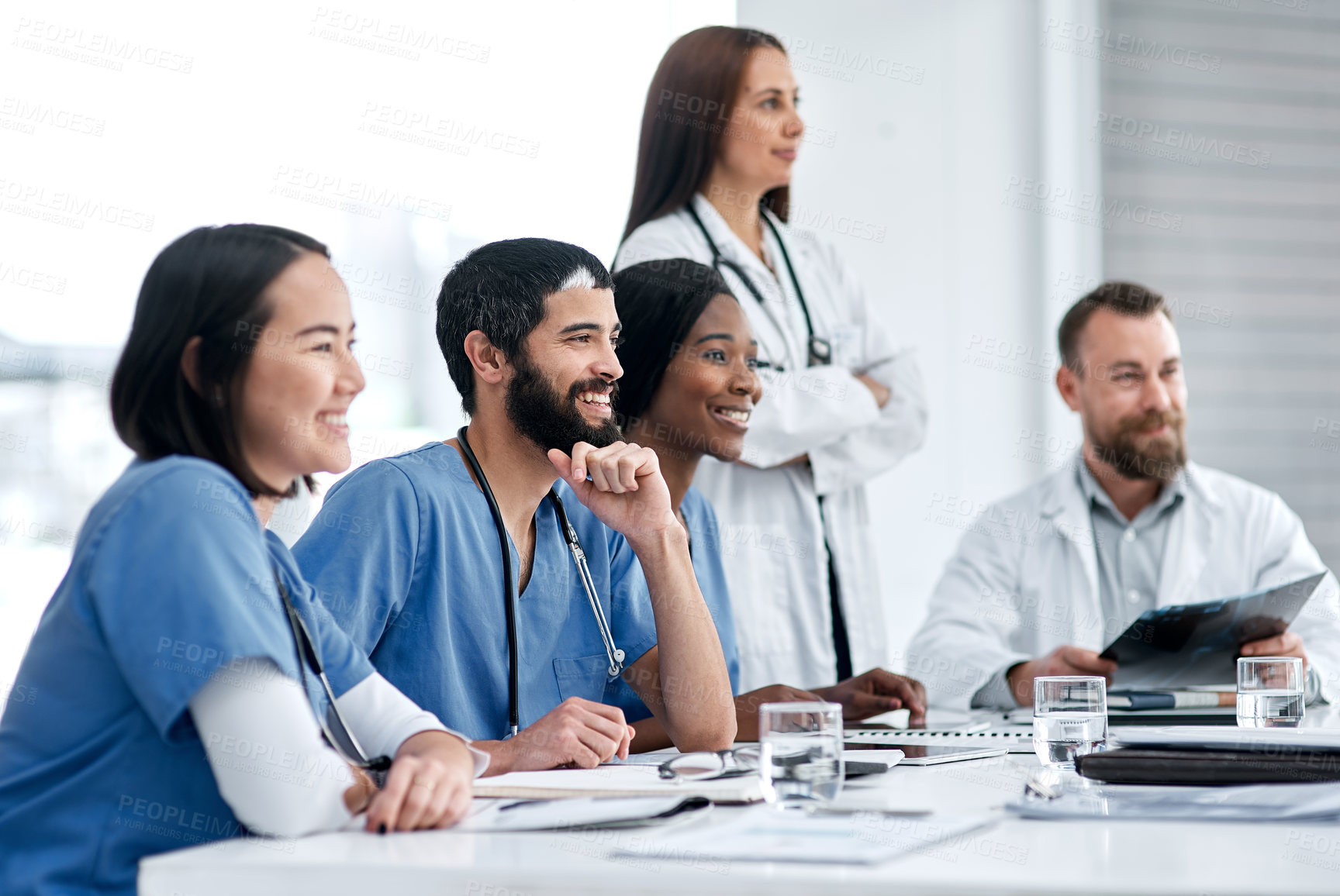 Buy stock photo Shot of a doctor sitting alongside his colleagues during a meeting in a hospital boardroom