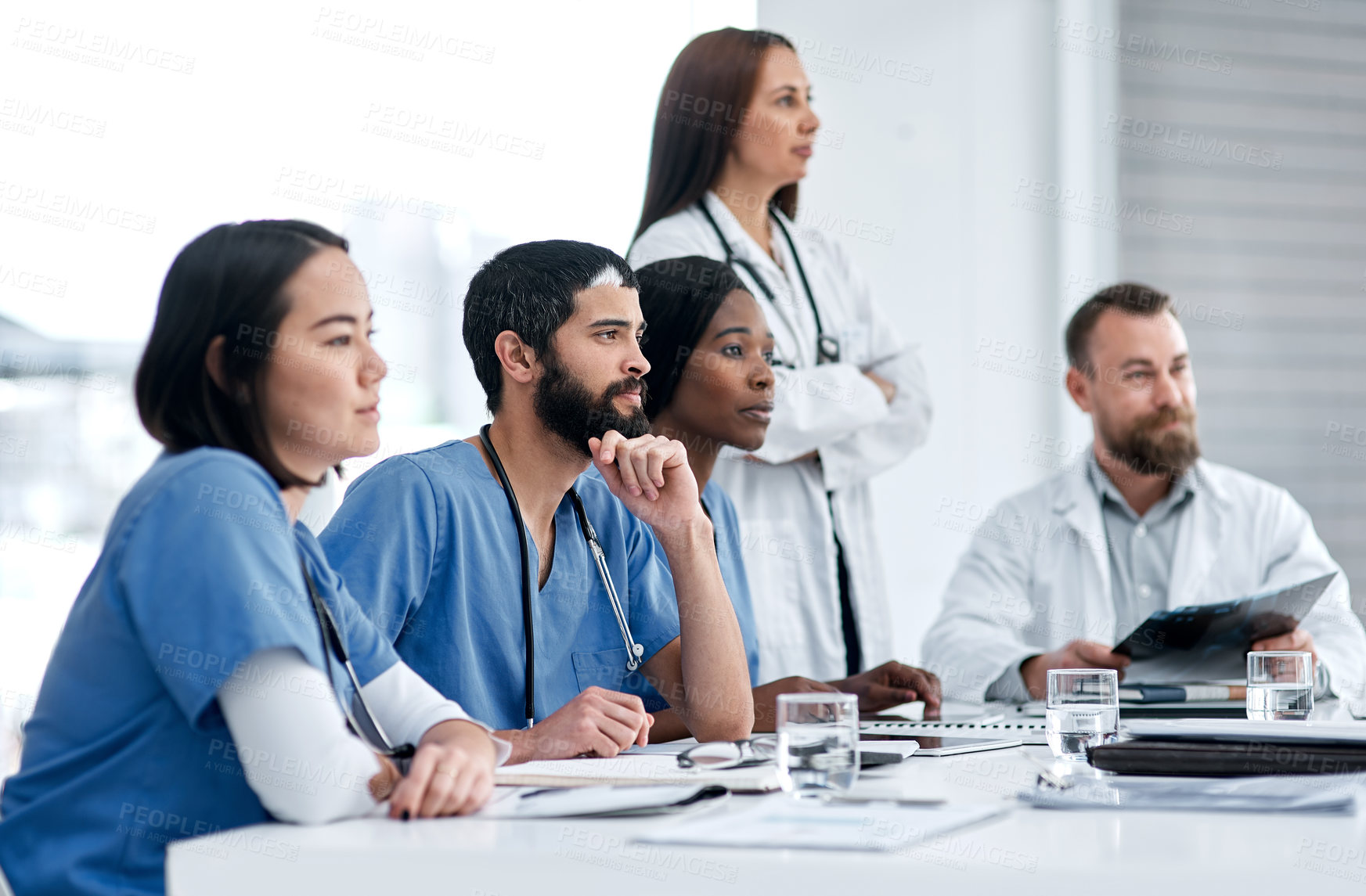 Buy stock photo Shot of a doctor sitting alongside his colleagues during a meeting in a hospital boardroom