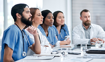 Buy stock photo Shot of a doctor sitting alongside her colleagues during a meeting in a hospital boardroom