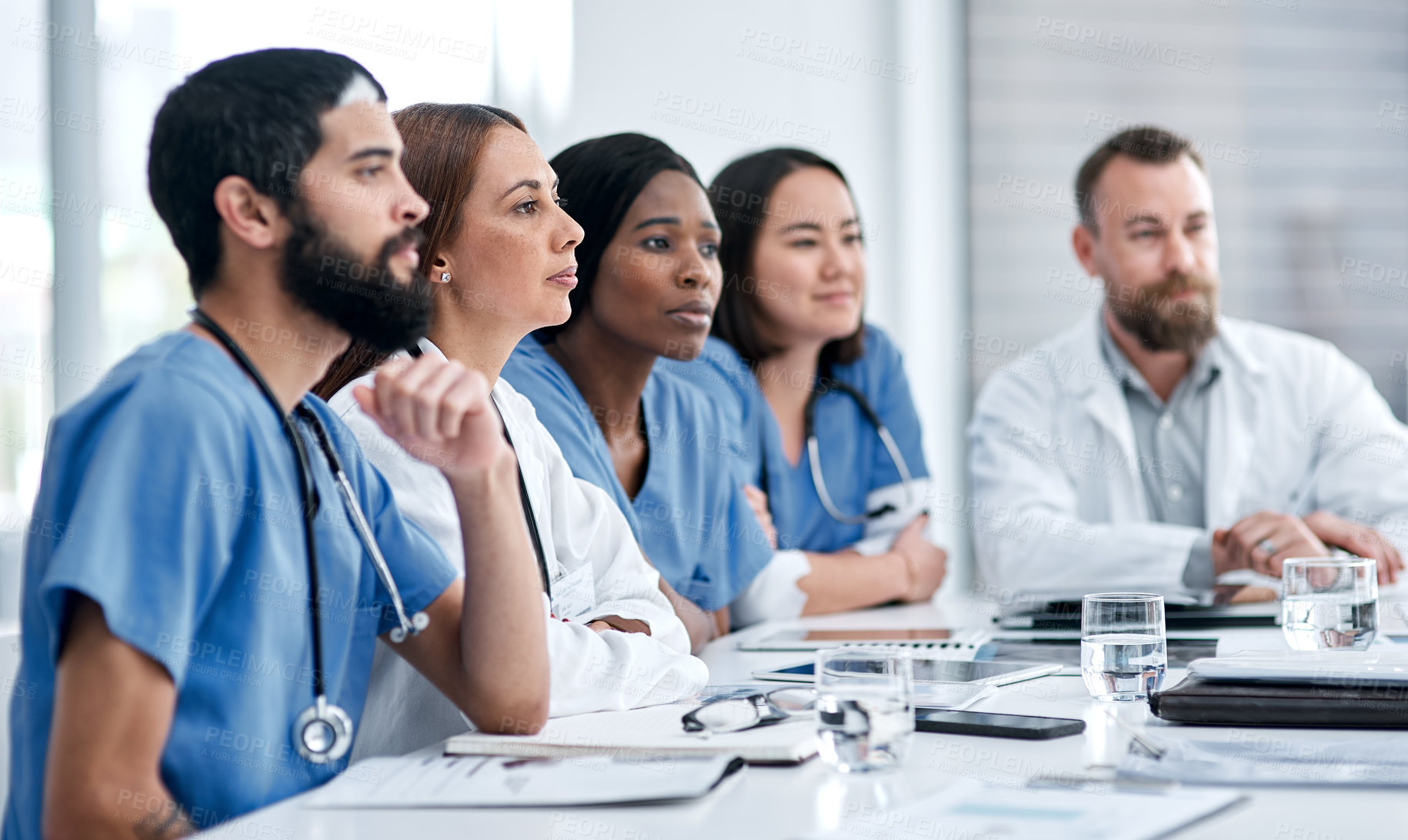 Buy stock photo Shot of a doctor sitting alongside her colleagues during a meeting in a hospital boardroom