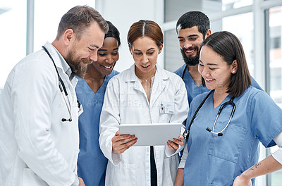 Buy stock photo Shot of a group of medical practitioners using a digital tablet together in a hospital