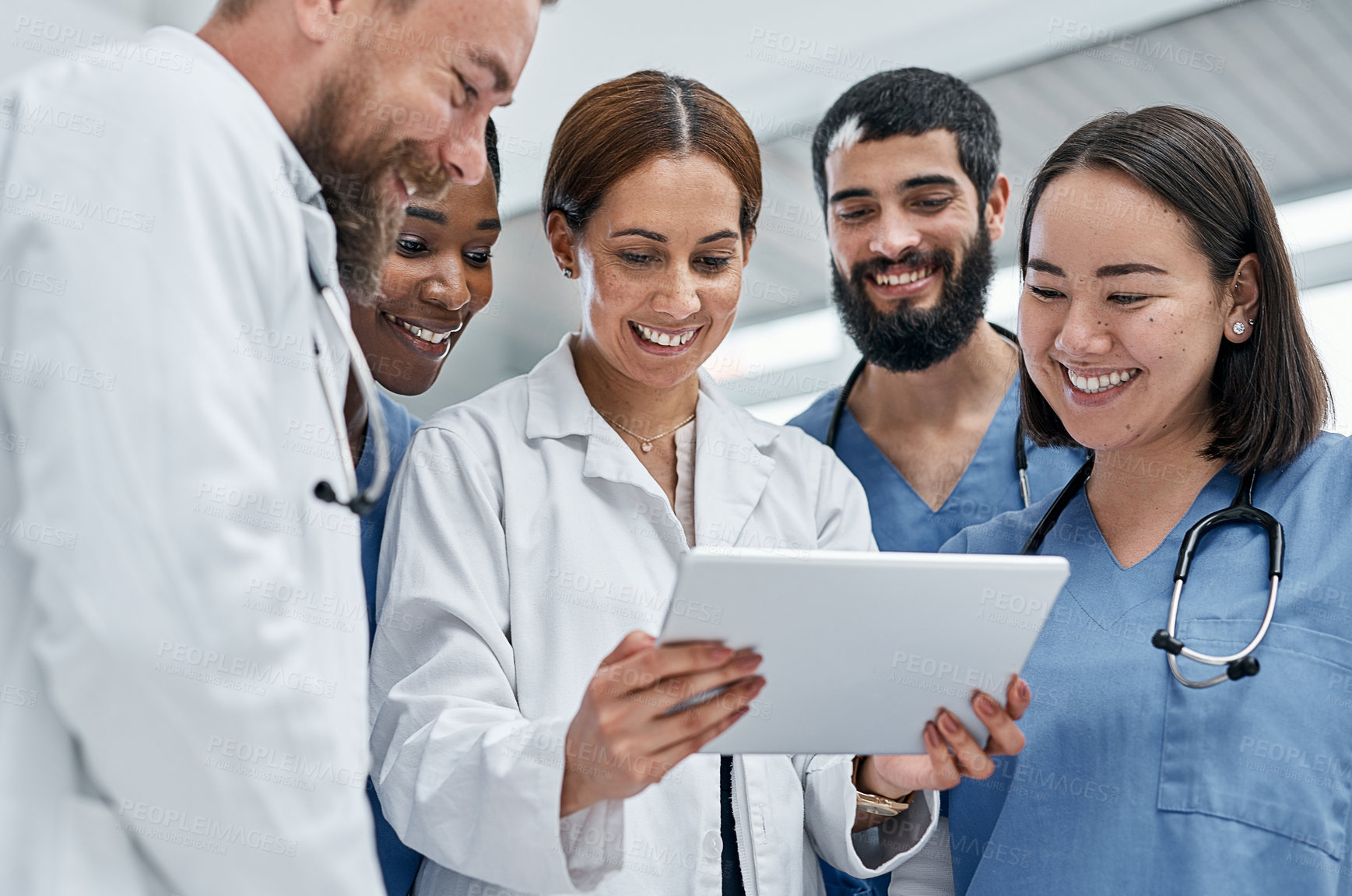 Buy stock photo Shot of a group of medical practitioners using a digital tablet together in a hospital