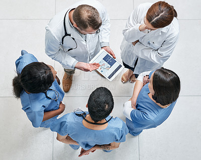 Buy stock photo High angle shot of a group of medical practitioners using a digital tablet together in a hospital