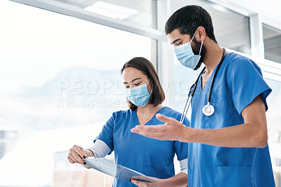 Buy stock photo Shot of two medical practitioners going through notes together in a hospital