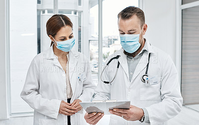 Buy stock photo Shot of two doctors going through notes in a hospital