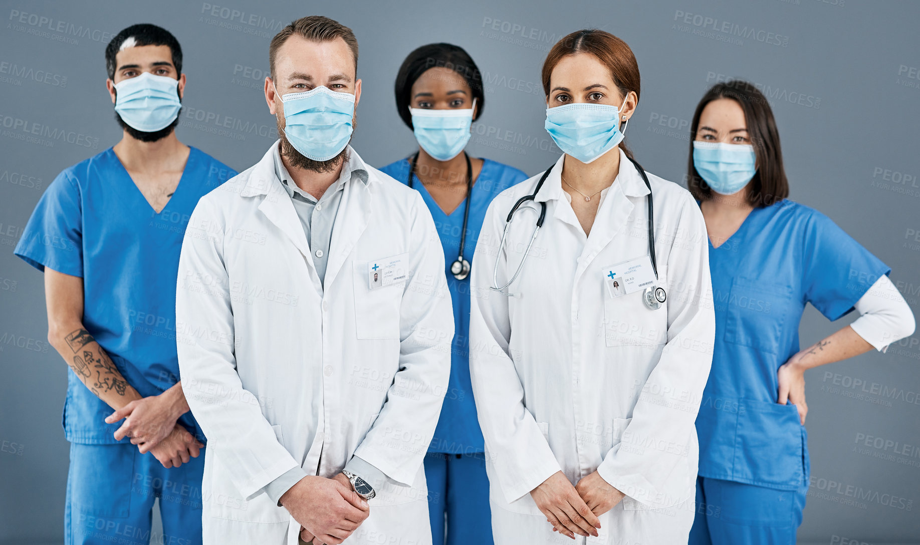 Buy stock photo Portrait of a group of medical practitioners wearing face masks against a grey background