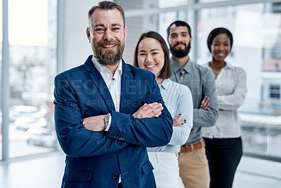 Buy stock photo Portrait of a businessman standing in an office with his colleagues in the background