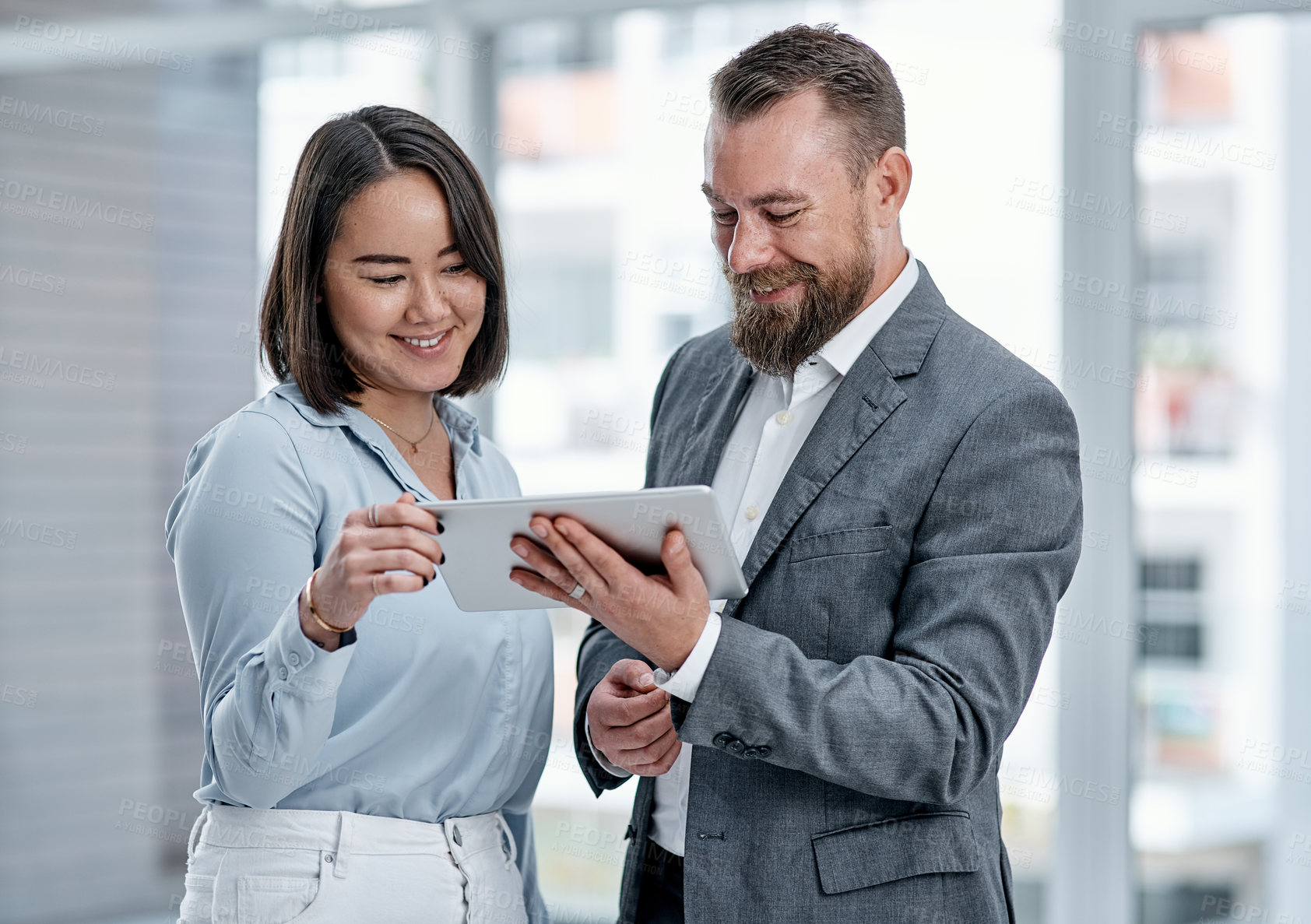 Buy stock photo Shot of two businesspeople using a digital tablet together in an office