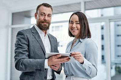 Buy stock photo Portrait of two businesspeople using a digital tablet together in an office