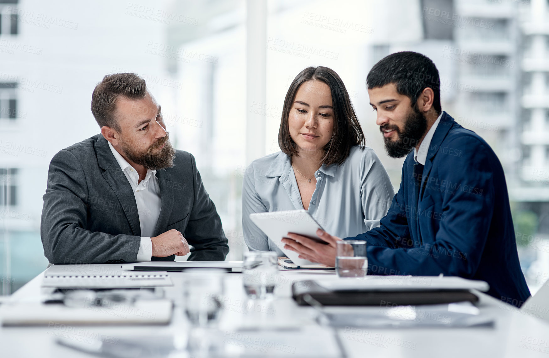 Buy stock photo Shot of a group of businesspeople working together on a digital tablet in an office