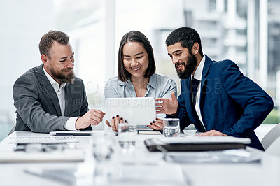 Buy stock photo Shot of a group of businesspeople working together on a digital tablet in an office