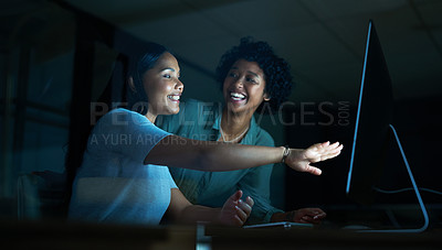 Buy stock photo Shot of two young businesswomen using a computer together during a late night at work